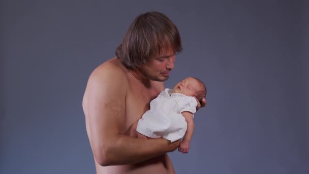 Junger Vater hält und küsst sein neugeborenes Baby. — Stockvideo