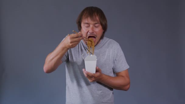 O gosto do homem é comer comida. Sorrindo homens segurando caixa branca com macarrão chinês . — Vídeo de Stock