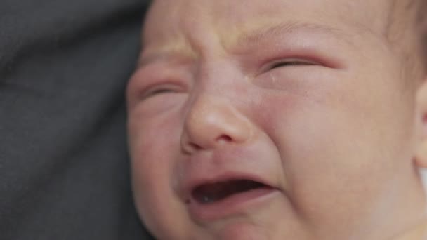 Primer plano de la cara de un bebé recién nacido en los primeros días que se despierta y abre los ojos. Un bebé recién nacido hace muecas a través de un sueño. Recién nacido en los primeros minutos de vida . — Vídeo de stock