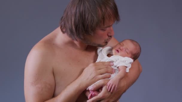 骄傲的父亲抱着他的女婴，看着彼此。爸爸抱着新生儿擦鼻涕,笑了.慢动作. — 图库视频影像