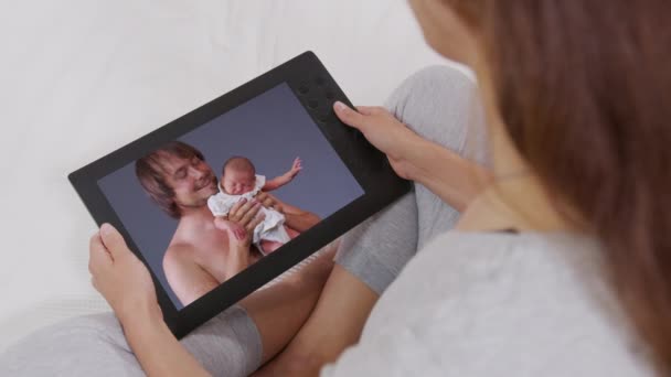 소파에서 쉬면서 집에 있는 디지탈 태블릿으로 아이들 과 손 자녀들 과 이야기를 나누는 이 젊은 여성의 뒷모습. 행복 한 가족. 온라인 채팅. — 비디오