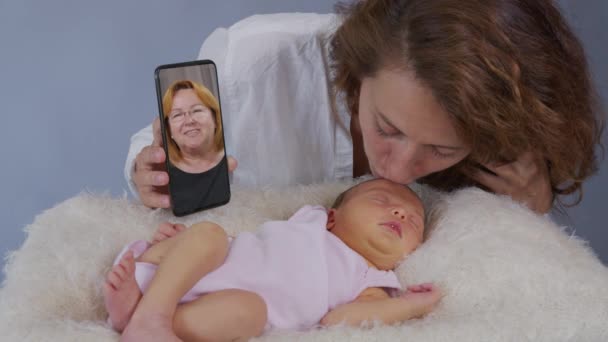 Jeune mère et bébé avoir un chat vidéo. femme utilisant smartphone agitant à la petite fille bénéficiant de la connexion familiale. — Video