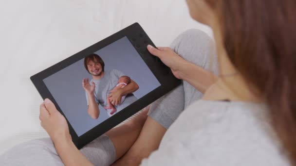 Evde dijital tablet kullanarak çocuklarıyla ve torunlarıyla konuşurken kanepede dinlenen genç bir kadın. Mutlu bir aile. çevrimiçi sohbet. — Stok video