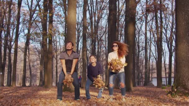 Famille s'amuser dans le parc d'automne. Maman père et fils vomissent des feuilles jaunes, amusement. — Video