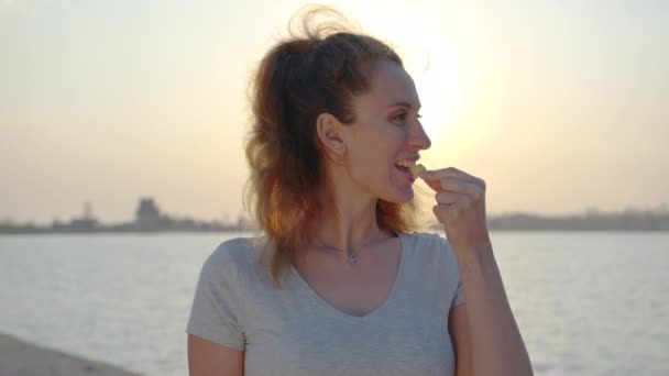 Mujer comiendo galleta al atardecer . — Vídeos de Stock