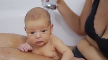 Yeni doğmuş bebek evde banyoda banyo yapıyor. Yeni doğan bebek için hijyen ve sağlık hizmeti.