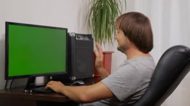 Genç adam video konferans mesafesinde web kamerasıyla sohbet ediyor ve bilgisayardaki sanal sohbet uygulamasını kullanarak gülüyor. Sosyal uzaklık iletişimi.