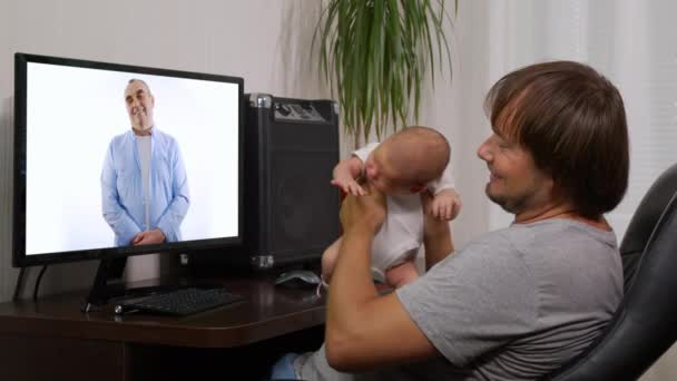 Мужчина с младенцем дома, имеющий видео-чат на ПК, взаимодействующий вместе в режиме онлайн во время социального дистанцирования и самоизоляции в карантинной изоляции. — стоковое видео