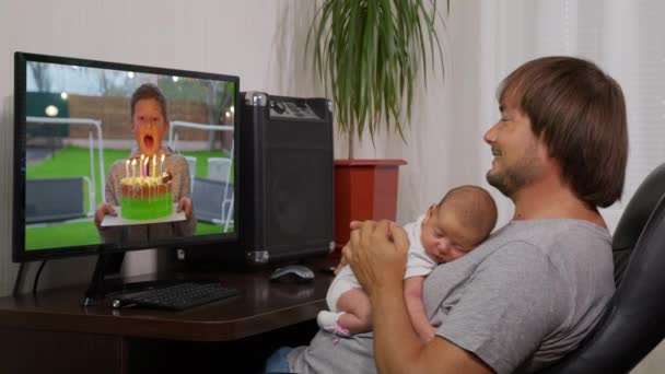 Vista sobre el hombro de la joven PC en la que viendo un video de un niño pequeño soplando velas en el pastel en su cumpleaños. Primer plano. . — Vídeos de Stock