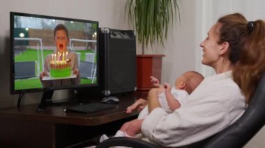 Küçük bir çocuğun doğum gününde pastaya mum üflediği videoyu izleyen genç bayanın omzunun üstünden bakın. Yakın çekim..
