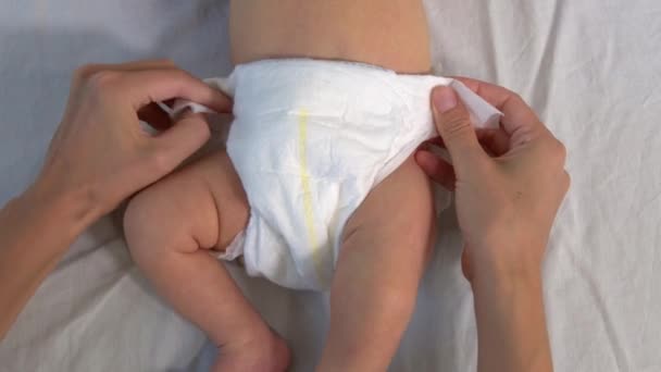 Anya pelenkát cserél az újszülött babáján. Egy újszülött kicsi lábai. A gyerek mozgatja a lábait. Új életet. A baba száraz bőre. — Stock videók