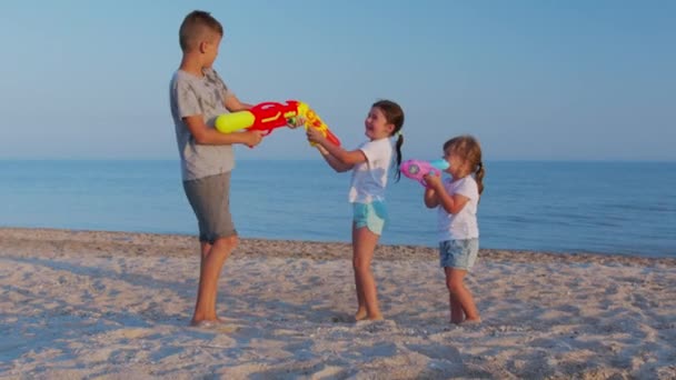 Κοριτσάκια και αγόρια στη θάλασσα. Παιδιά που παίζουν με νεροπίστολα. — Αρχείο Βίντεο