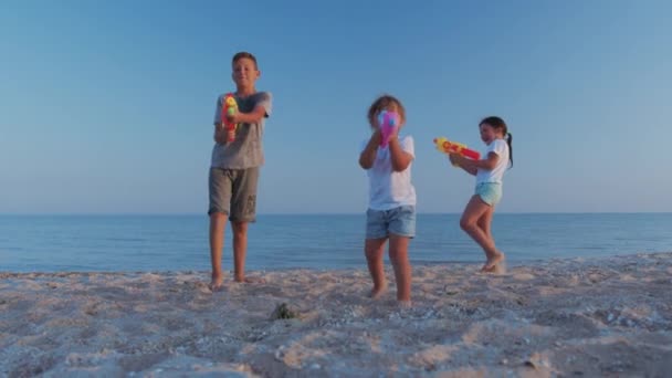 Niñas y niños en el mar. Niños jugando con pistolas de agua. — Vídeo de stock