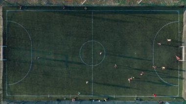 Hava atışı, iki takımın top oynadığı açık hava, üst manzara. Dışarıda futbol maçı, işaretli yeşil alan, elinde topla koşuşturan oyuncular..