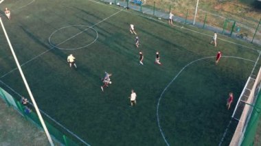 Hava atışı, iki takımın top oynadığı açık hava, üst manzara. Dışarıda futbol maçı, işaretli yeşil alan, elinde topla koşuşturan oyuncular..