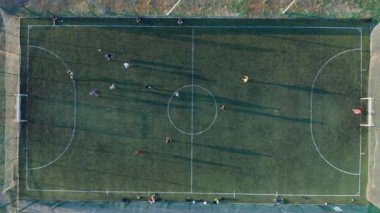 Hava atışı, iki takımın top oynadığı açık hava, üst manzara. Dışarıda futbol maçı, işaretli yeşil alan, elinde topla koşuşturan oyuncular..