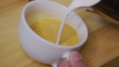 Profesyonel bir adam espresso ile süt dolduruyor..