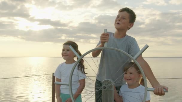 Kinderen aan een denkbeeldig stuurwiel bij zonsondergang. Gelukkige jeugd. — Stockvideo