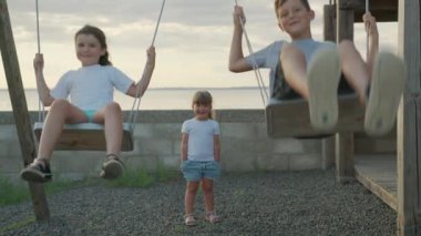 Farklı yaş ve cinsiyetten çocuklar salıncakta sallanıyor. Mutlu çocukluk kavramı.