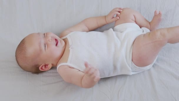 Aranyos mosolygós baba fekszik az ágyon. — Stock videók