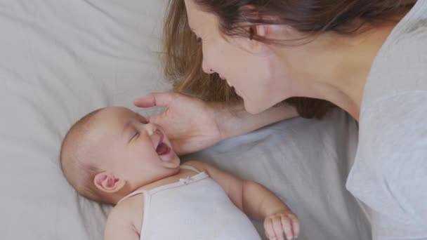 Nahaufnahme einer jungen Mutter, die morgens mit ihrem Neugeborenen in einem Kinderzimmer spielt. Konzept von Kindern, Baby, Elternschaft, Kindheit, Leben, Mutterschaft. — Stockvideo