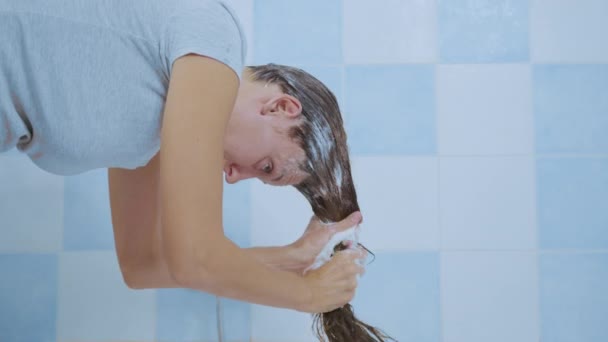 Jeune femme lave le shampooing de ses cheveux tout en. Concept de propreté des cheveux et du corps. — Video