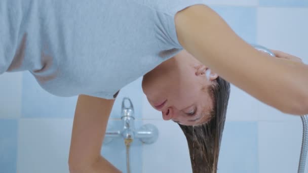 Jeune femme lave le shampooing de ses cheveux tout en. Concept de propreté des cheveux et du corps. — Video