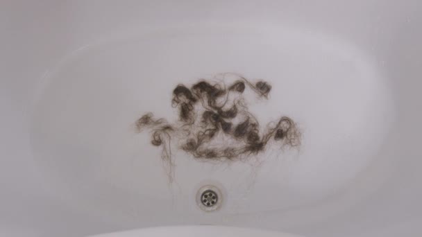 .Лёгкие волосы после мытья лежат в ванне. Проблема выпадения волос. — стоковое видео