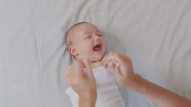 Egy közeli kép a fiatal anyáról, ahogy játszik az újszülött babájával egy óvodában egy reggel. Fogalom a gyermekek, baba, szülőség, gyermekkor, élet, anyaság. — Stock videók