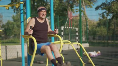 Aktif kıdemli, yaşlı, beyaz bir adam spor alanında fiziksel egzersiz yapıyor. Fitness eğlencesi. Yaşlılıkta sağlıklı yaşam tarzı.