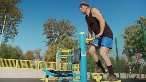 Un anciano retirado hace ejercicio en un campo de deportes afuera. concepto de estilo de vida saludable. — Vídeos de Stock