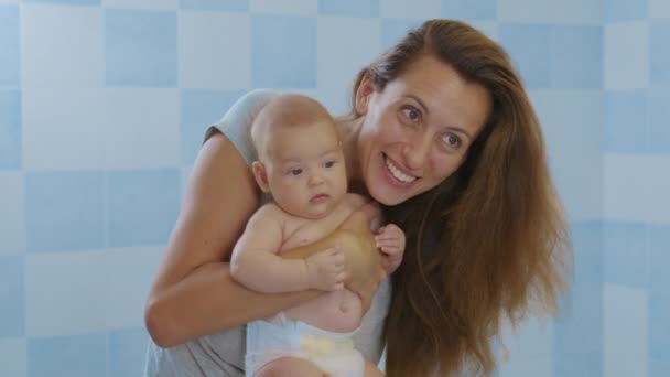 Mencintai lembut ibu muda memegang menggemaskan bayi perempuan cantik mencium anak kecil. — Stok Video