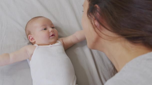 Egy közeli kép a fiatal anyáról, ahogy játszik az újszülött babájával egy óvodában egy reggel. Fogalom a gyermekek, baba, szülőség, gyermekkor, élet, anyaság. — Stock videók