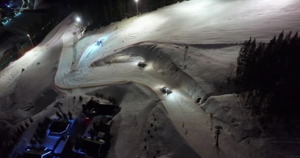 Letecký pohled. Snow Grooming Snowcat Machines Fix Trail on Ski Resort Slope at Night. — Stock video