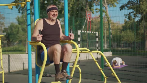 Un anciano retirado hace ejercicio en un campo de deportes afuera. concepto de estilo de vida saludable. — Vídeos de Stock