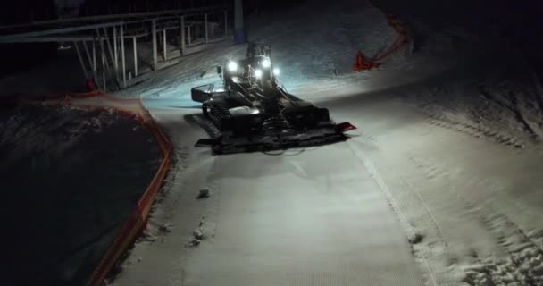 Letecký pohled. Snow Grooming Snowcat Machines Fix Trail on Ski Resort Slope at Night. — Stock video