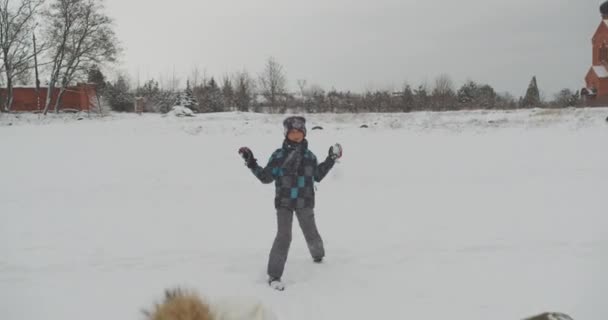 Familie vergnügt sich beim Spaziergang auf dem Land, wirft glitzernden Schnee und wirft Schneebälle auf den Jungen. — Stockvideo