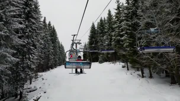 Leere Skilifte auf der Seilbahn über der Skipiste in den österreichischen Alpen mit Skifahrern im Winter in Österreich. — Stockvideo