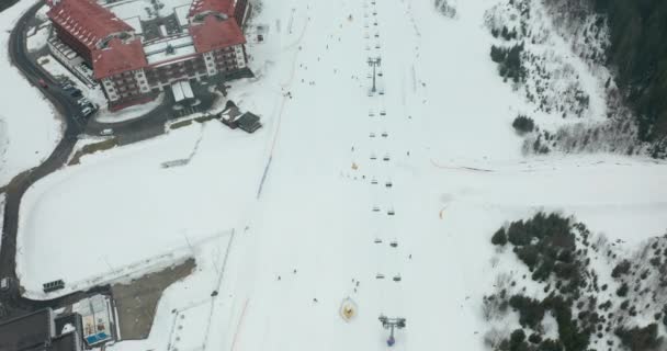 Luftaufnahme des Skilifts für den Transport von Skifahrern und Snowboardern auf der verschneiten Skipiste. — Stockvideo