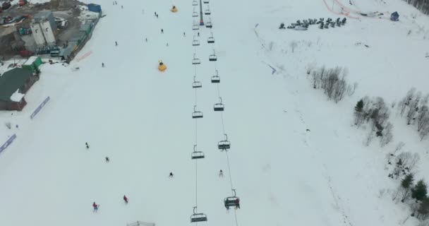 Vista aérea: estância de esqui, declive e elevador de cadeira. Cableway levanta esquiadores para a montanha. Actividade de Inverno. — Vídeo de Stock