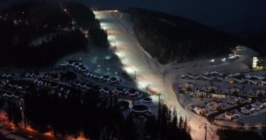 Uçan ileri dağ kayak merkezinin modern evleri karanlık dağların turistik köyleri arasındadır. Gece aydınlatması..