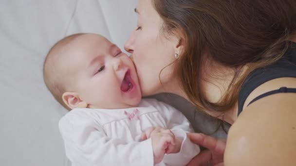Egy közeli kép a fiatal anyáról, ahogy játszik az újszülött babájával egy óvodában egy reggel. Fogalom a gyermekek, baba, szülőség, gyermekkor, élet, anyaság, anyaság. — Stock videók