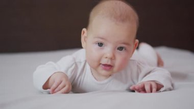 Küçük güzel kızın gülümsemesinin yavaş çekimini kapat. Bebek gülümsemesinin kapalı mekândaki portresi..