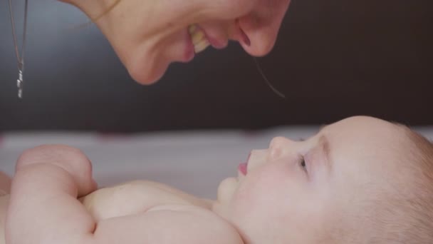 Zbliżenie. Matka delikatnie całuje dziecko ciesząc kochającą mamę figlarnie troszcząc się o malucha w domu dzieląc połączenie z jej nowonarodzonego dziecka. Zdrowa opieka nad dziećmi. — Wideo stockowe