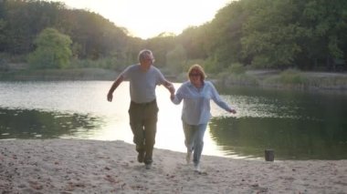 Parkta birlikte yürürken el ele tutuşan yaşlı bir çift. Romantik yaşlı çift dinleniyor, doğada dinleniyor. Mutluluk insanlar yaşam tarzı .