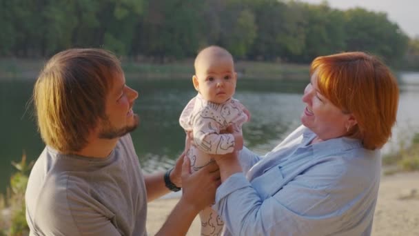 Grand-mère tenant bébé dans les bras à l'extérieur. Lien grand-parent avec le petit-enfant. — Video