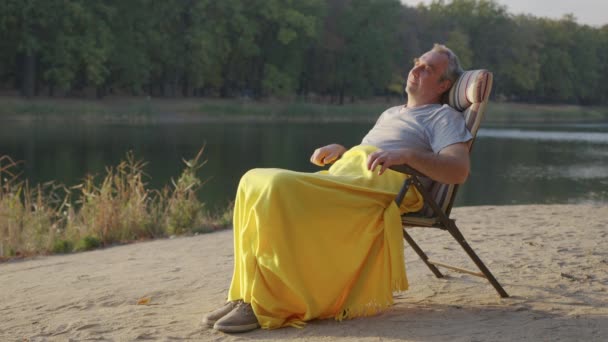 노인이 아름다운 타오르는 일몰을 즐기고 있다. 할아버지는 야외 생활에 대해 생각하고 자연을 즐긴다. 평화. — 비디오