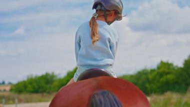 Little cute girl is riding horse in a helmet, training and practicing.