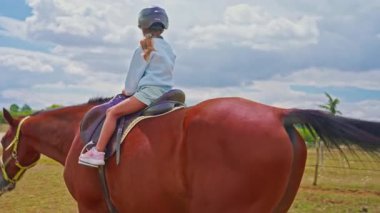 Little cute girl is riding horse in a helmet, training and practicing.