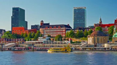 View of Hamburgs waterfront and citycenter and ships and boats passing along the Elbe River at sunset in Hamburg, Germany.